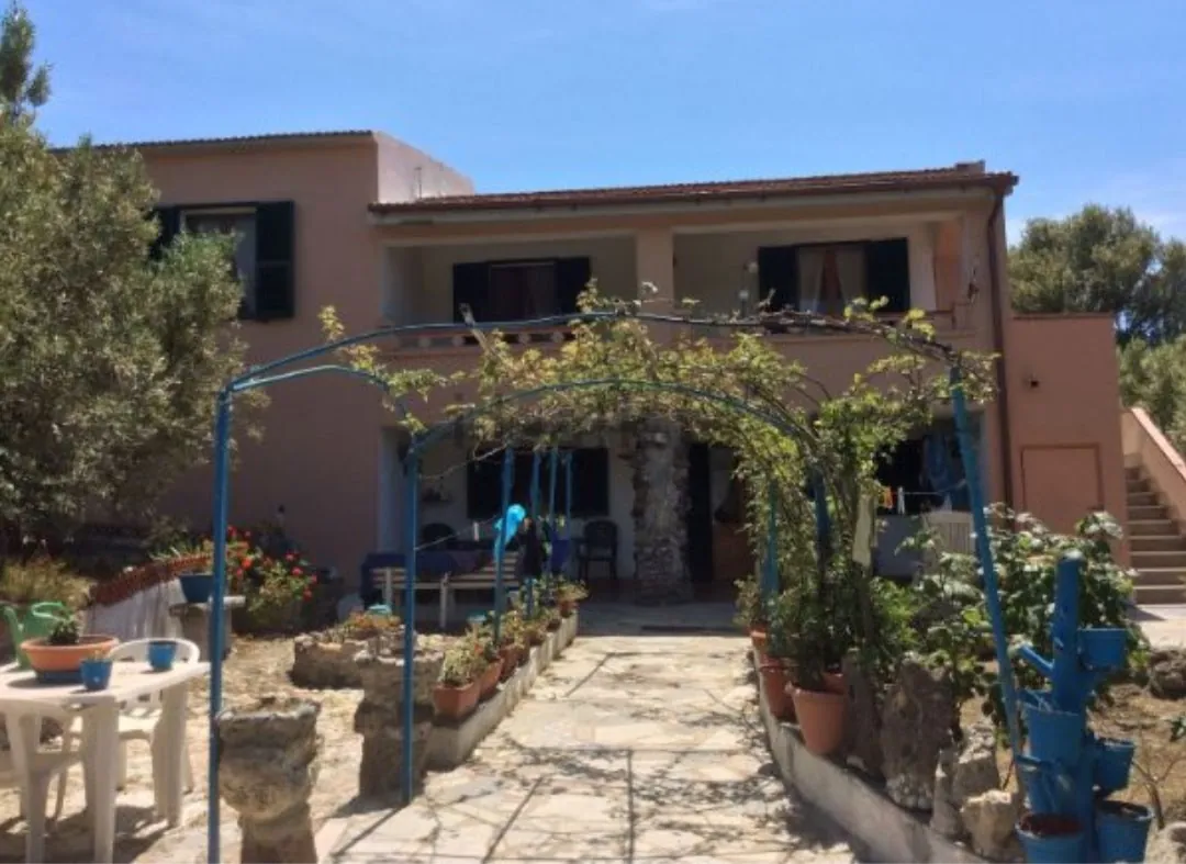 L'ingresso di Villa Rosa sotto il pergolato di ferro azzurro, con vasi di fiori lungo il vialetto