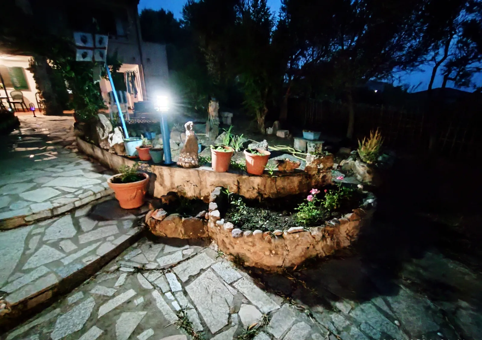 Il giardino di notte con la fontana di pietra illuminata