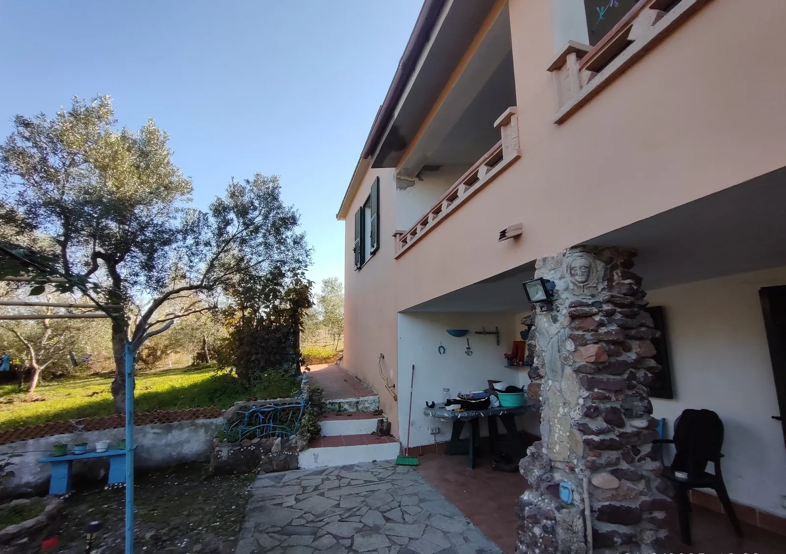 L'angolo coperto sotto il balcone, con la scala esterna e il pilastro in pietra