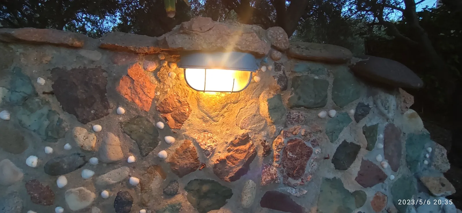 Muro in pietra e ciottoli di fiume con una lanterna accesa