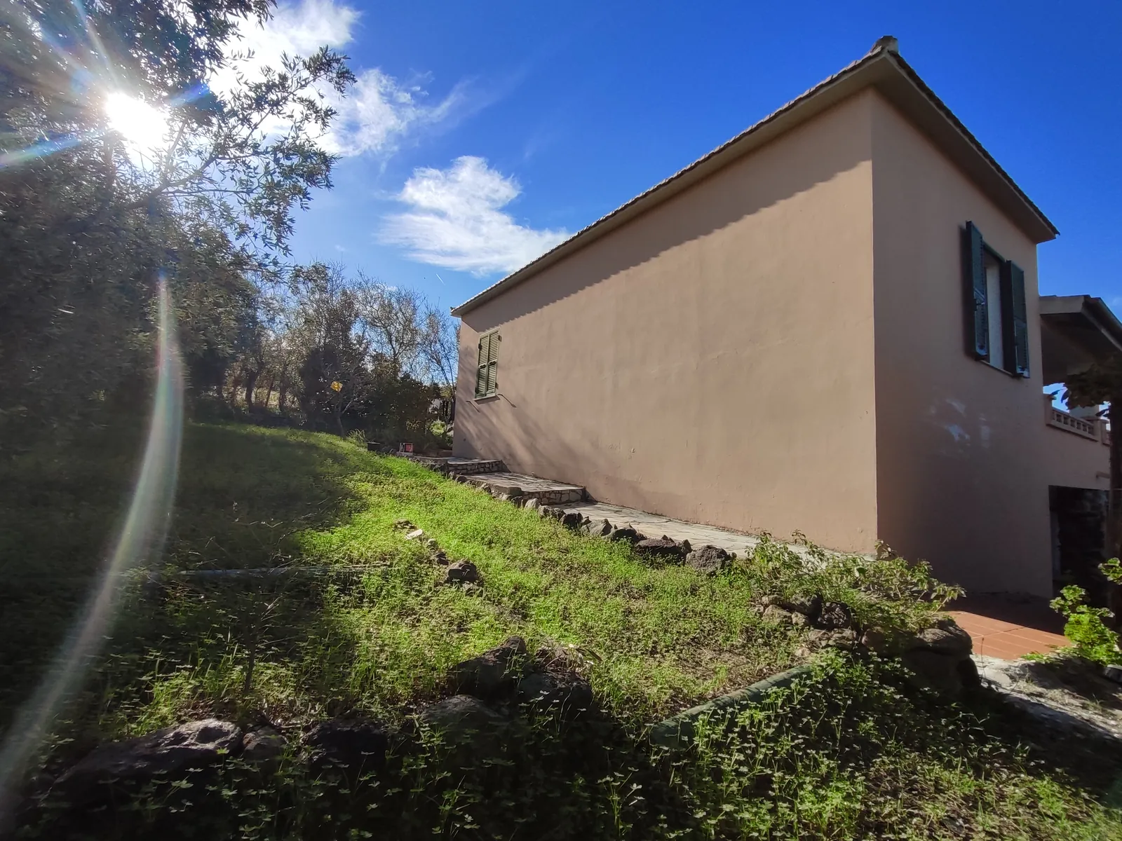 La casa vista dal prato in controluce, con il sole alto